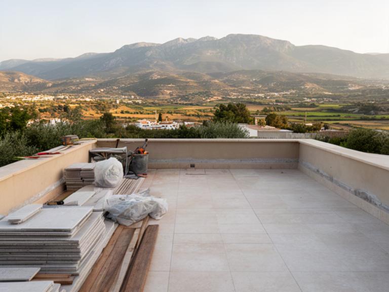 Terraza en construcción con vistas a las sierras de Córdoba y materiales preparados para una reforma exterior