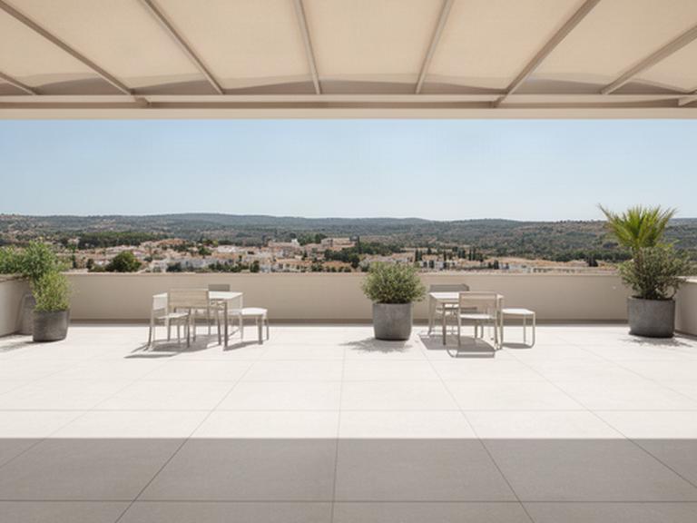 Gres porcelánico de gran formato en una terraza exterior con líneas limpias y luz mediterránea