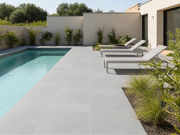 Grandes piezas de porcelánico gris en una terraza luminosa junto a una piscina